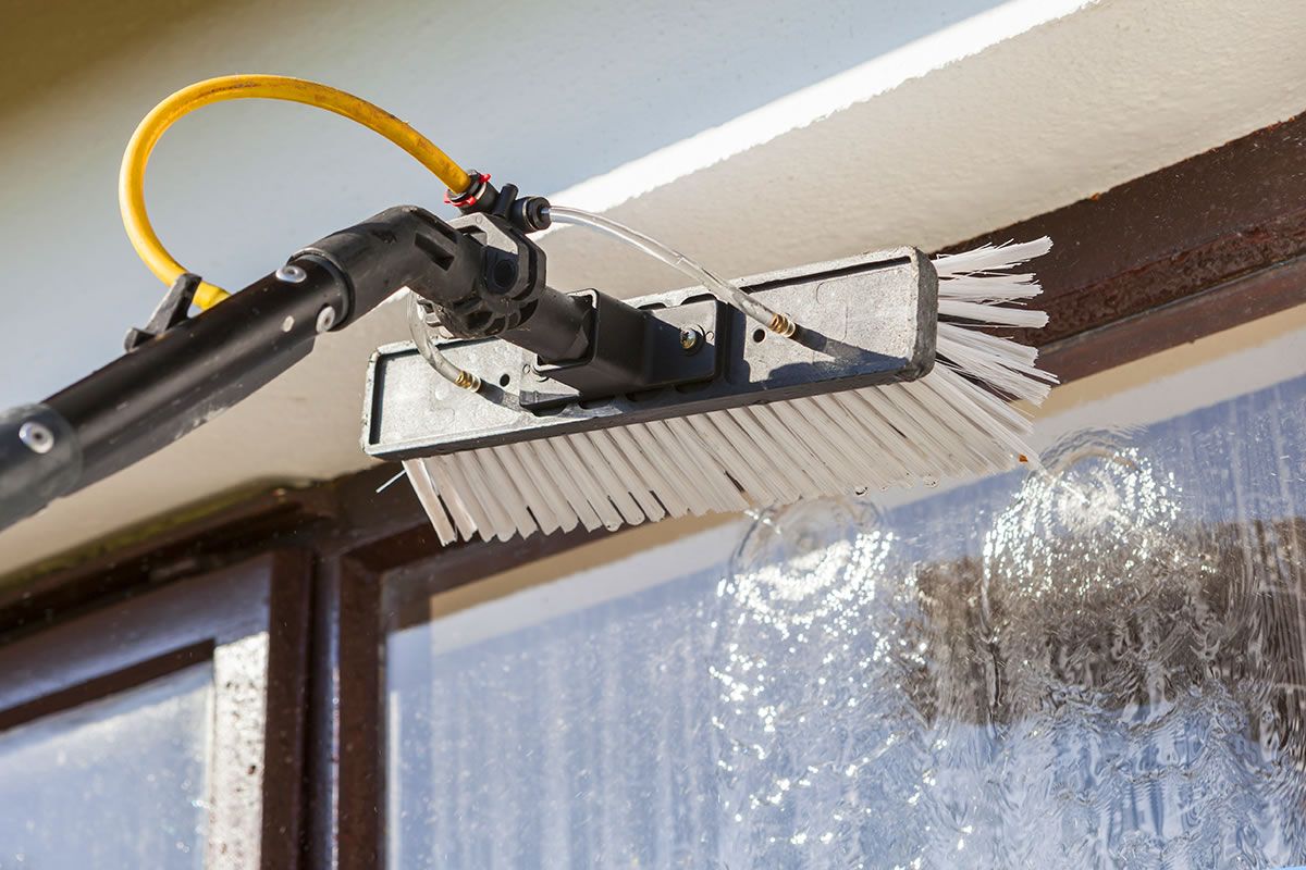 Water-fed pole brush cleaning a window with purified water